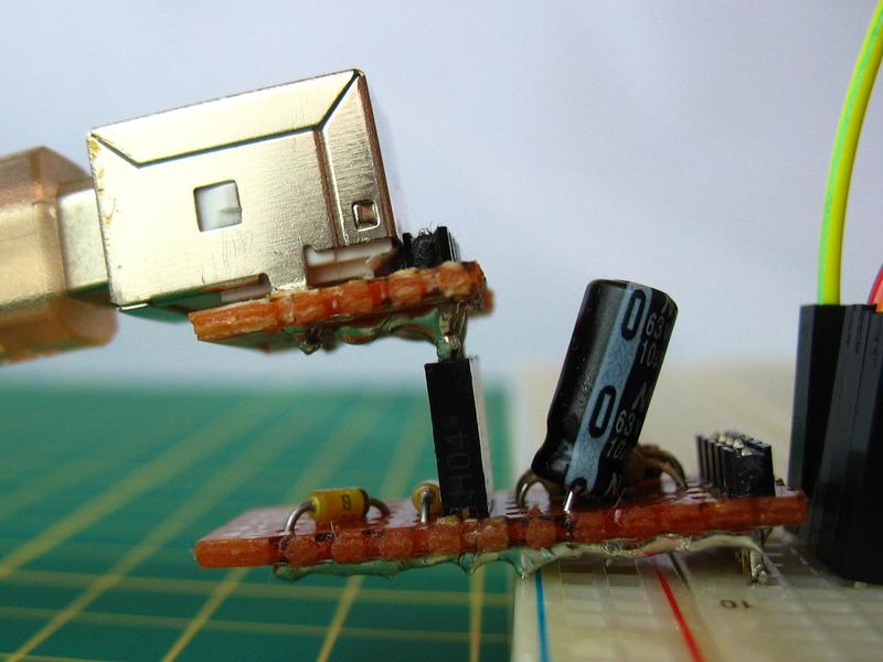 V-USB development board plugged into a breadboard, with a heavy USB cable pulling it down