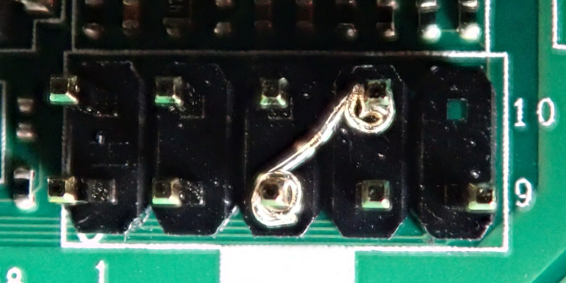 Motherboard front panel pin header with two pins connected by a piece of wire.